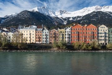 Barevné domy u řeky Inn s Alpami v pozadí v Innsbrucku